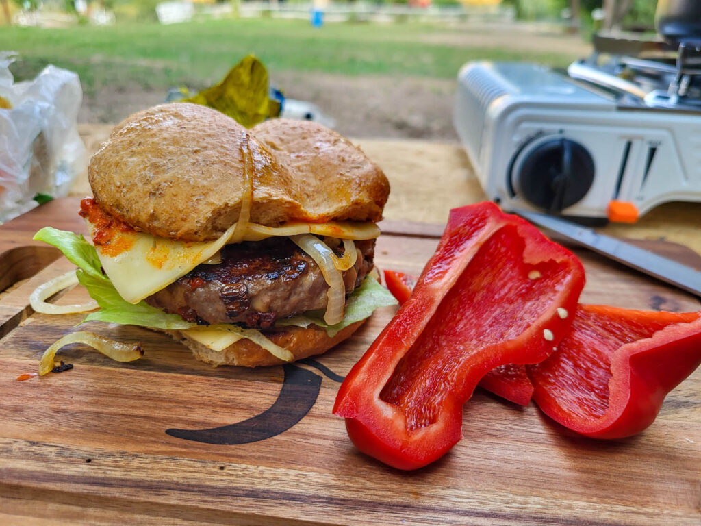 A delicious burger and two slices of paprika.